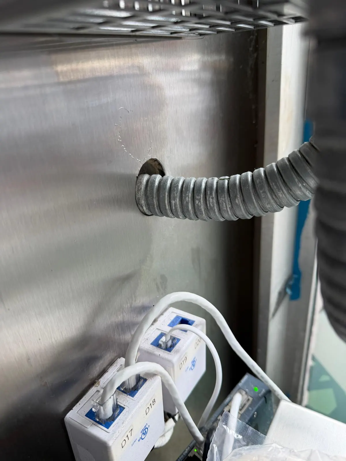 Flexible conduit entering an oversized hole in a stainless steel wall